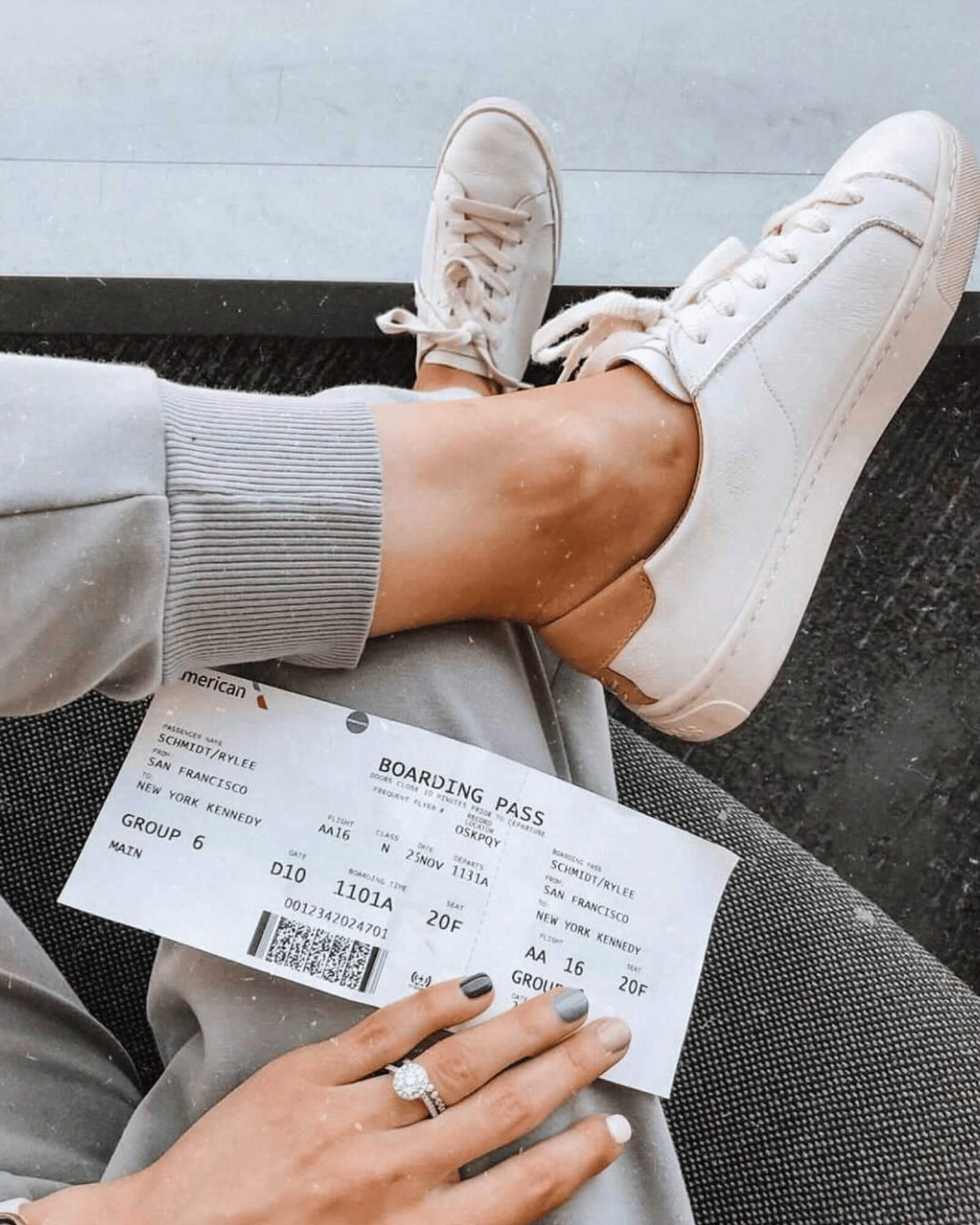 woman wearing white Ibiza Sneakers crossing her legs with a boarding pass in her hand