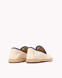 Men's ivory espadrille shoes with navy blue piping on gray background