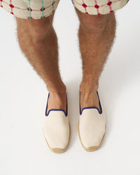 Adult man wearing ivory espadrilles with navy piping around it