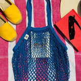 Blue bag laying on a towel outside