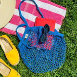 Blue bag laying on a towel outside