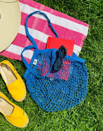 Blue bag laying on a towel outside