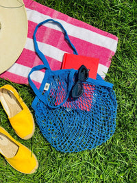 Blue bag laying on a towel outside