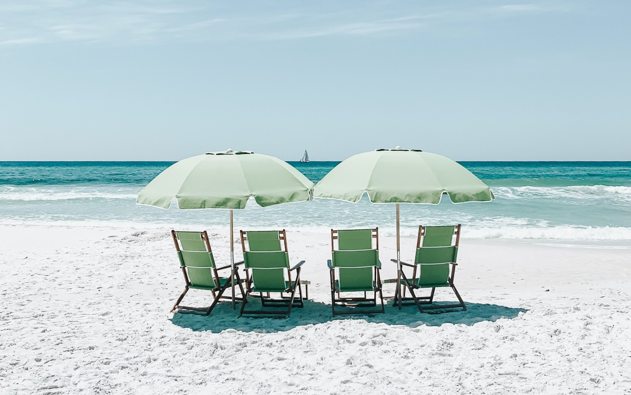 two umbrellas and chairs by the beach