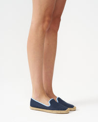 Adult woman wearing navy espadrilles with light blue piping around it