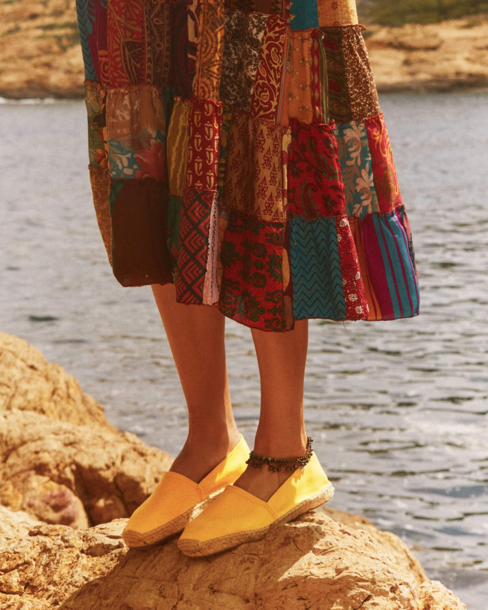 woman standing on a rock in yellow shoes