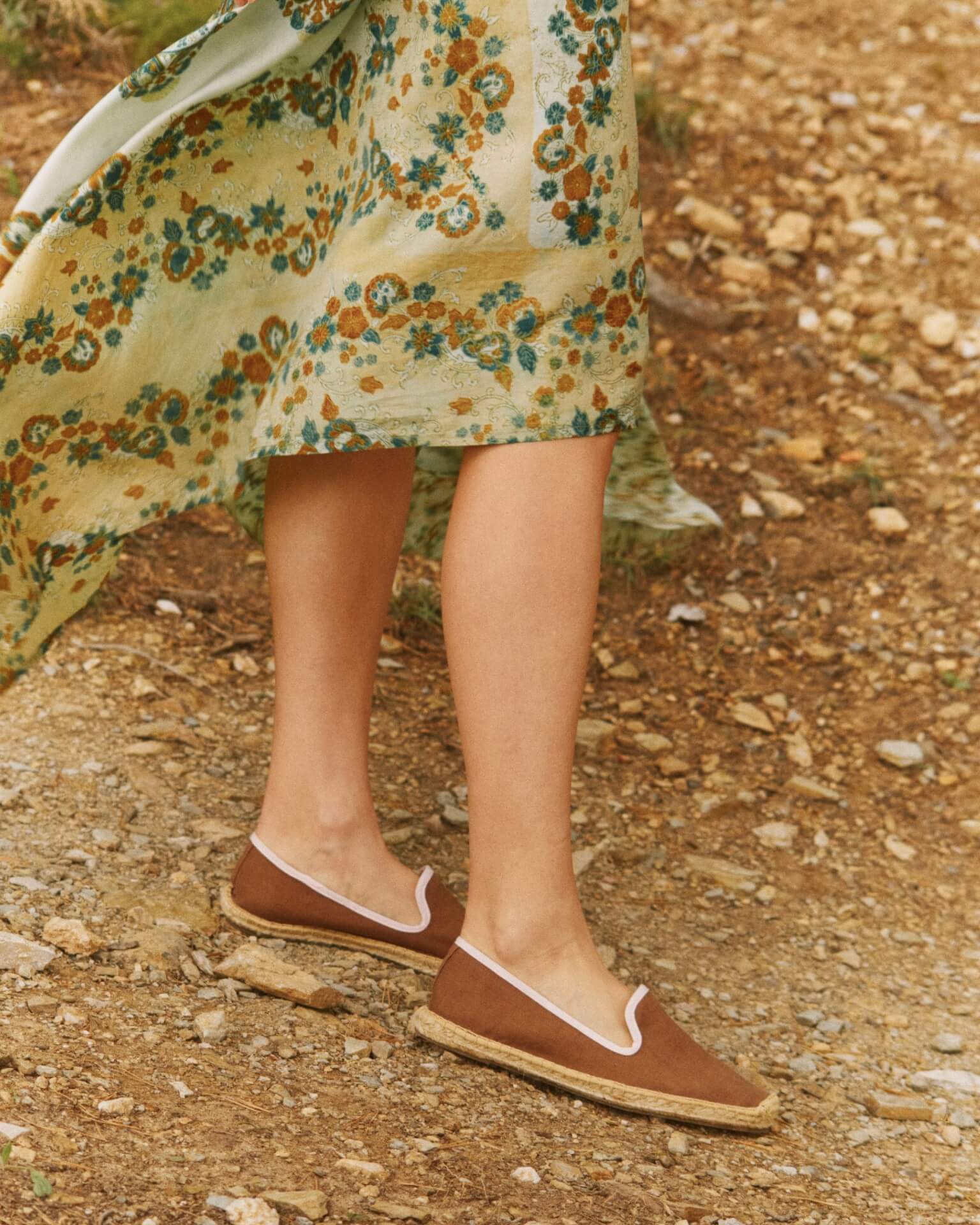 Adult woman wearing brown espadrilles with pink piping around it
