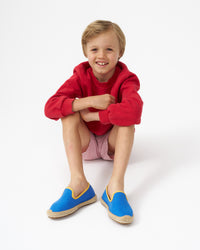 Blond boy wearing blue espadrilles with yellow piping
